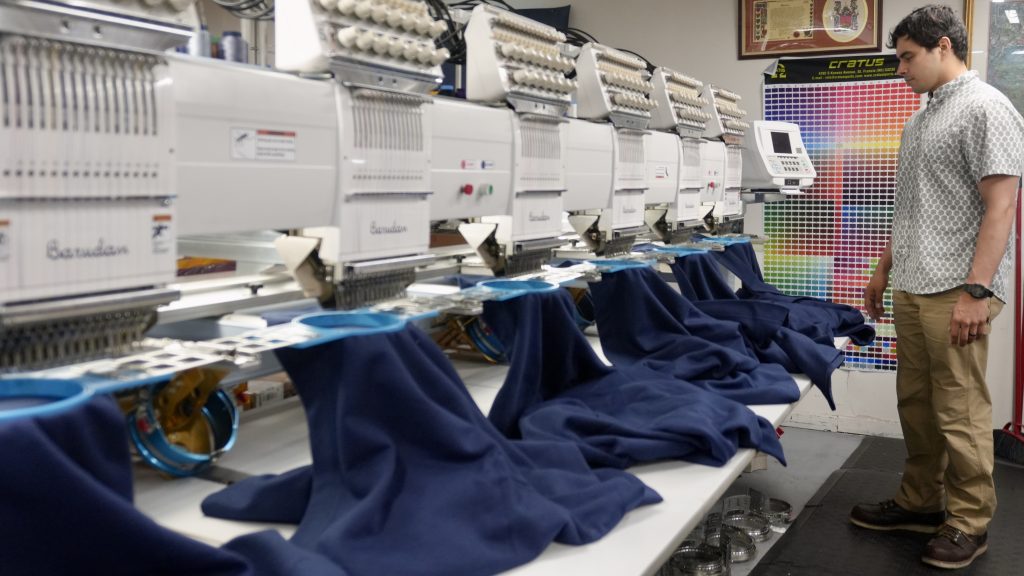 Jordan Gonzales embroidering blankets on a six-head embroidery machine