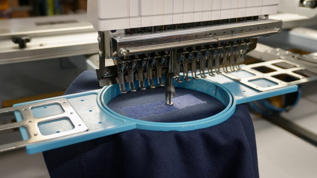 Close-up of a Barudan embroidery machine hoop stitching custom apparel at Generation Embroidery